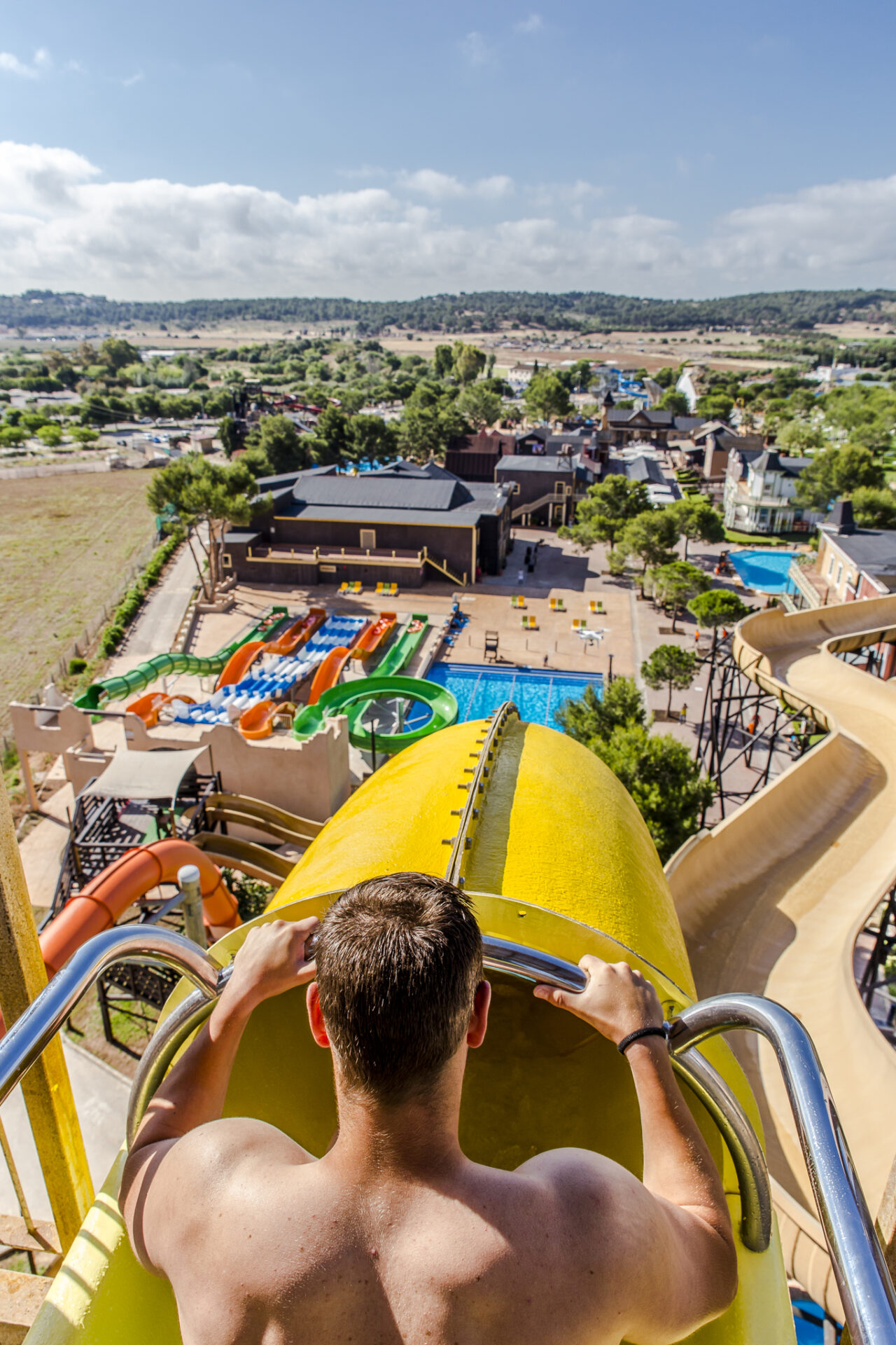 Yellow water slide at Western Waterpark Mallorca with riders splashing into the pool on a sunny day